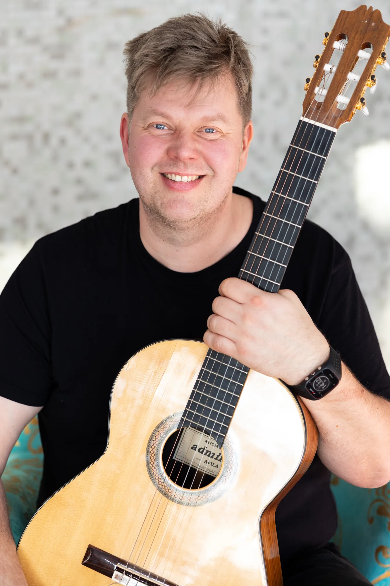 Mikko Malmivaara smiling with guitar